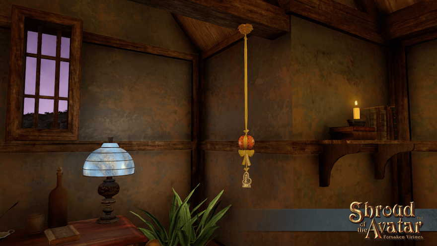 A cloved orange pomander, tied with a yellow ribbon and with a silver candle of love ornament below it, hangs by a desk from a rafter in a small Benefactor home.