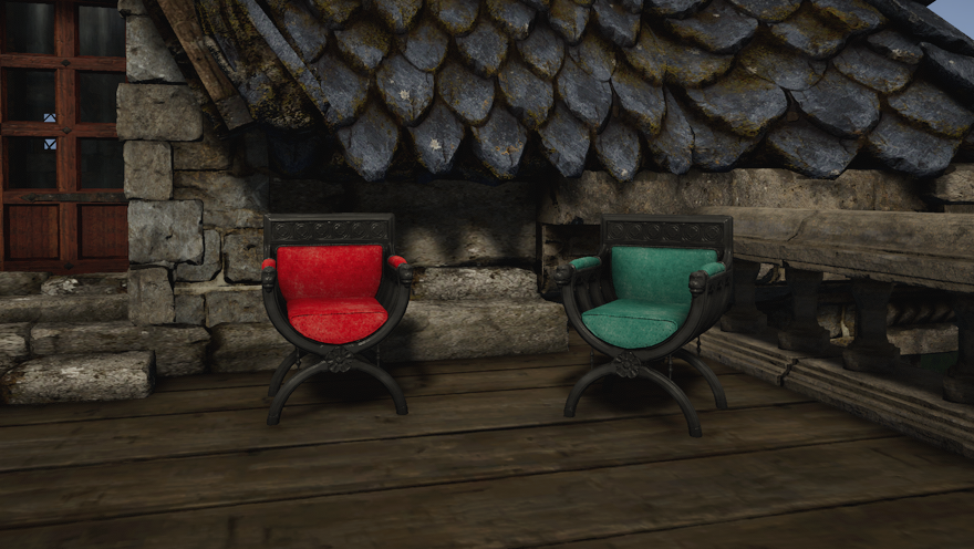 Two brown wood curule armchairs, one with red cushions and one with dyed dark aqua cushions, sit on the terrace of a stone house.
