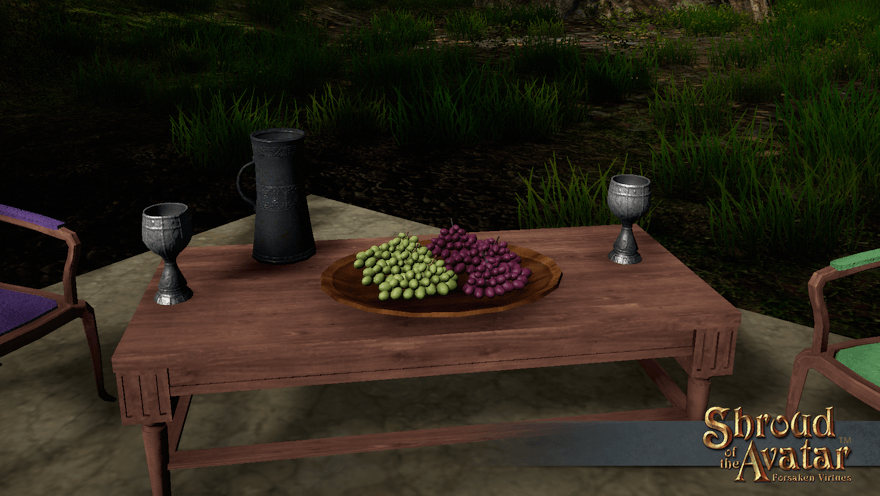 Bunches of red and green grapes sit on a wooden platter on a patio coffee table at the edge of the forest.