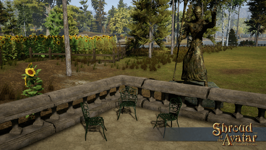 Three green iron chairs sit on an Estgard patio in front of a fenced field of sunflowers, guarded by a large statue of an elf mage.