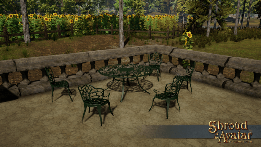 Five green iron chairs are arrayed around a large matching table on an Estgard patio in front of a fenced field of sunflowers.
