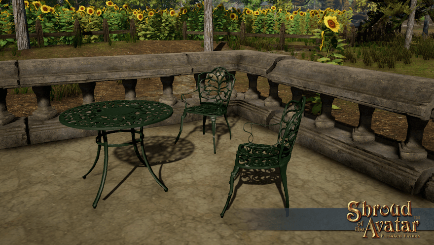 Two green iron chairs bracket a small matching table on an Estgard patio in front of a fenced field of sunflowers.